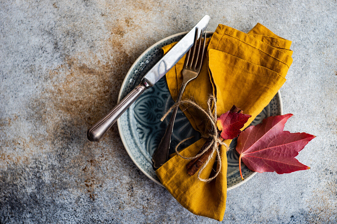 Autumnal table setting with red wild grape leaves on concrete background