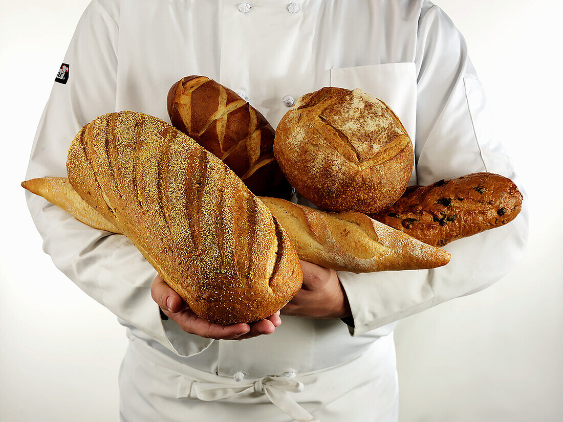 A variety of artisnal breads held in the arms of a chef