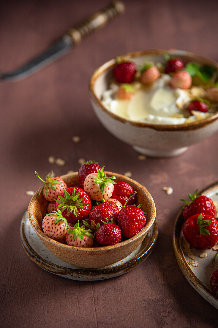 Frische Erdbeeren, im Hintergrund Erdbeeren mit Joghurt und Honig