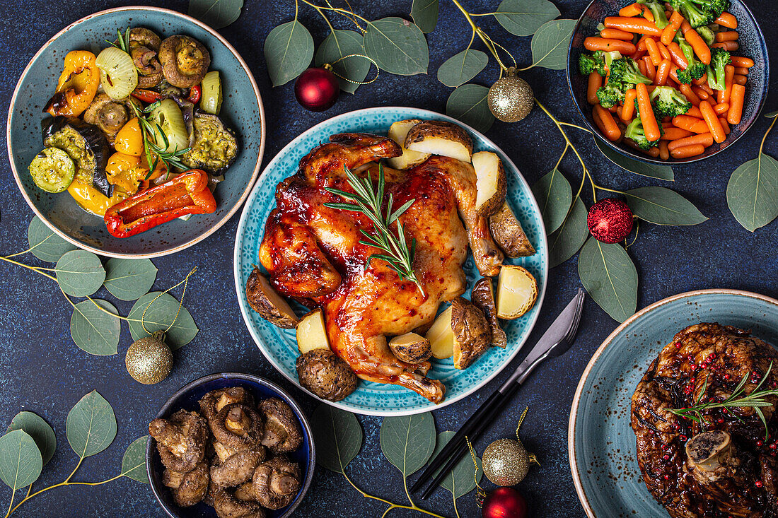 Weihnachtstisch mit festlichen Gerichten (Brathuhn, Schweinshaxe und Gemüse)