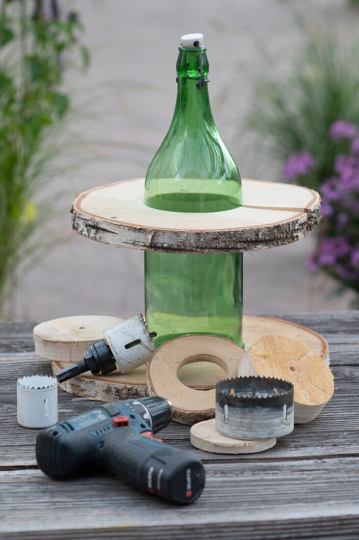 Make your own etagere from a bottle and wooden discs with a cordless drill and hole saw attachment