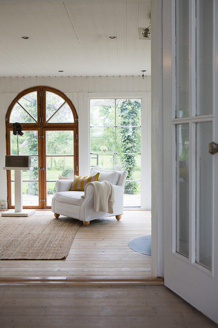 Blick auf weißen Sessel in hellem Zimmer mit Terrassenzugang