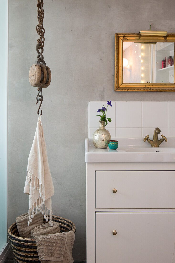 Washstand below gilt-framed mirror on grey concrete wall in bathroom