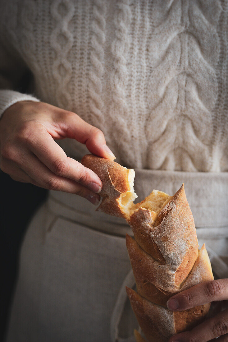 Woman holds baked baguettes in her hands