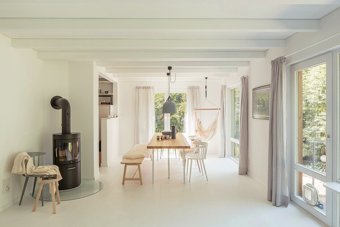 Wood-burning stove and dining area in open-plan interior with white walls