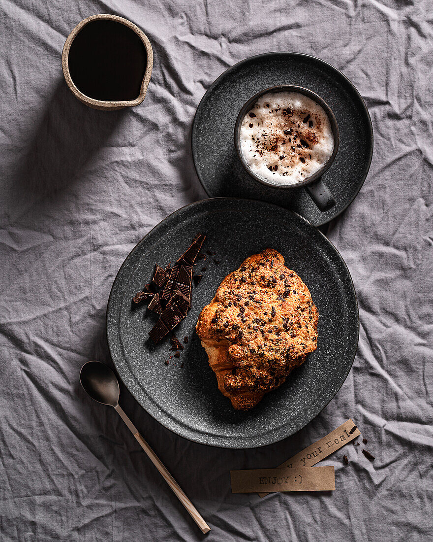 Schokoladencroissant mit einer Tasse Kaffee