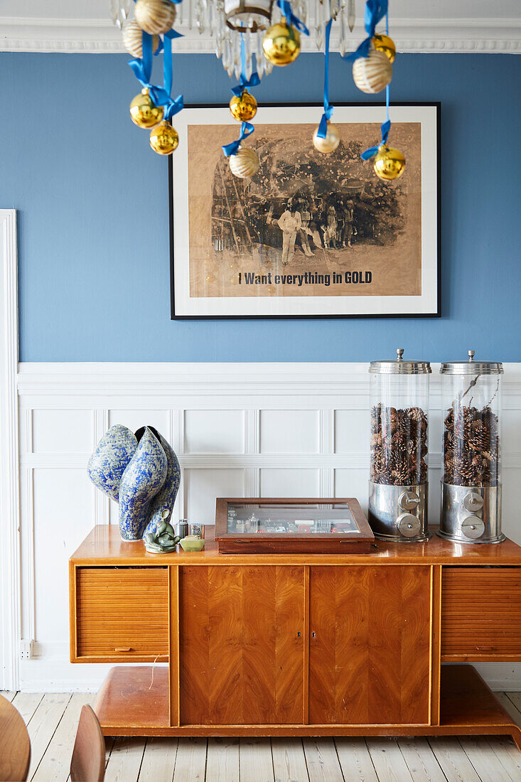 Dispensers and a ceramic sculpture on a sideboard in front of a blue wall with white panels