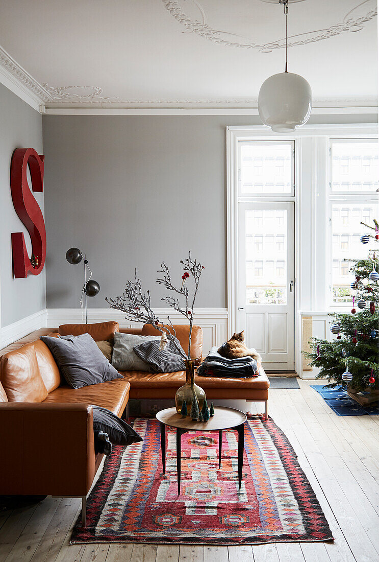 Cognacfarbene Ledercouch und Kelim-Teppich im Wohnzimmer mit hellgrauen Wänden