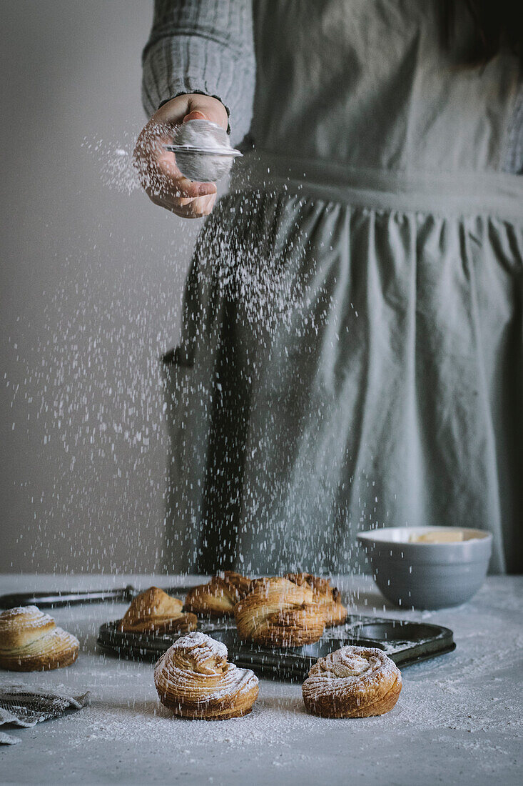 Cruffins being dusted with icing sugar