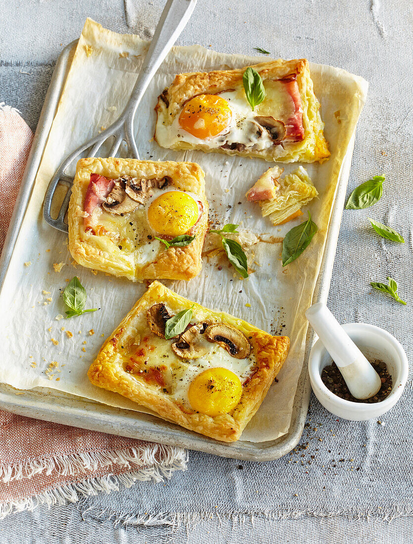 Kleine Blätterteig-Pizzen mit Schinken, Pilzen und Spiegelei