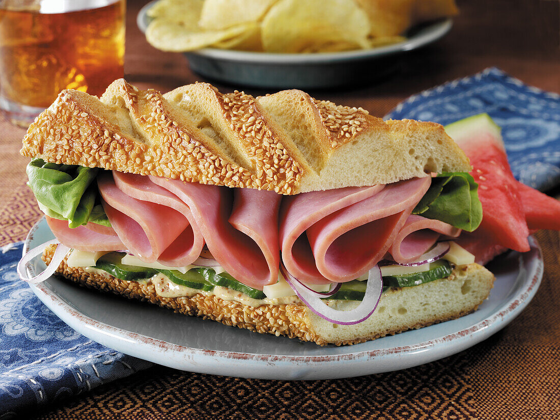 Ham and swiss cheese sandwich with lettuce, onions, cucumber and Dijon mustard on sesame baguette