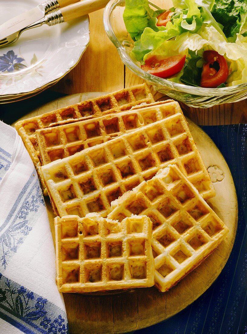 Four cheese waffles (one broken) on wooden board