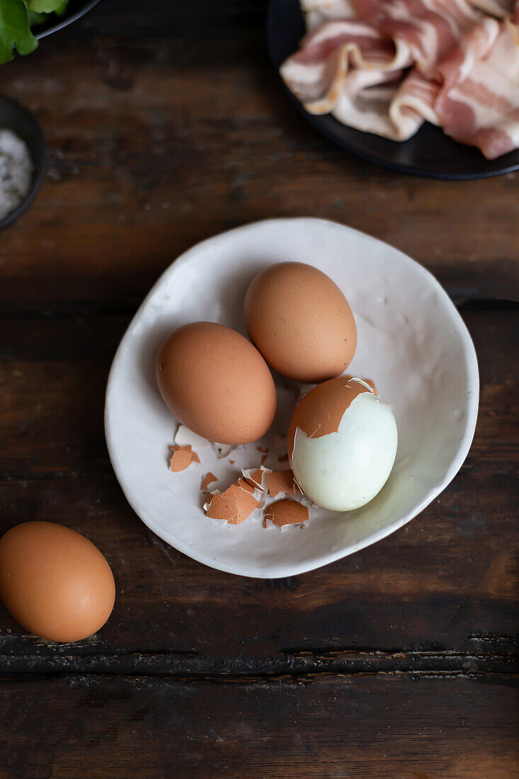 Hard-boiled eggs, one partially peeled