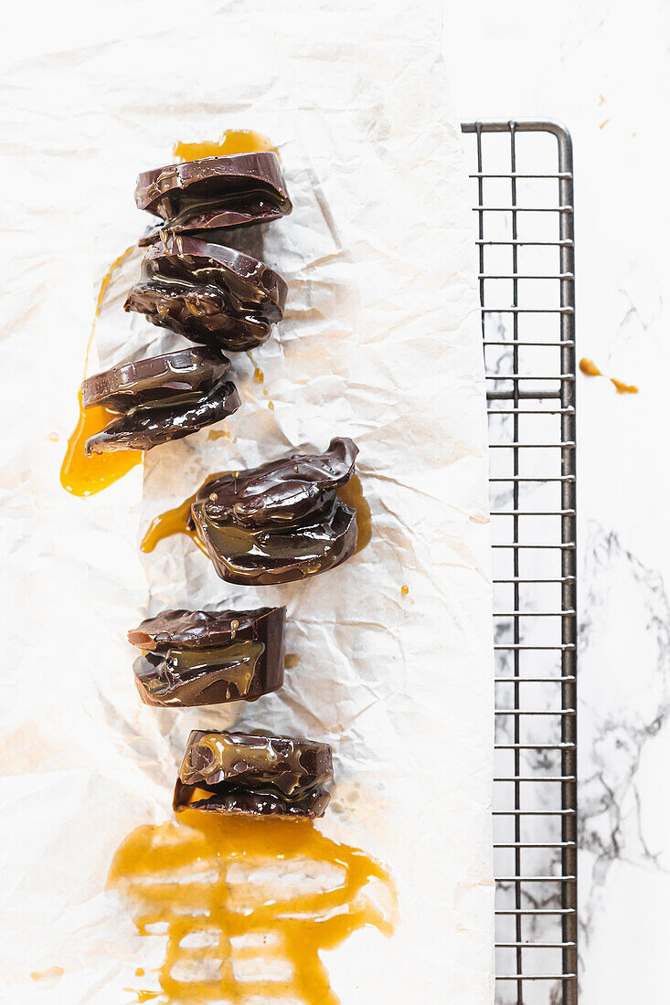 Chocolate and caramel bites, dripping sauce on white background