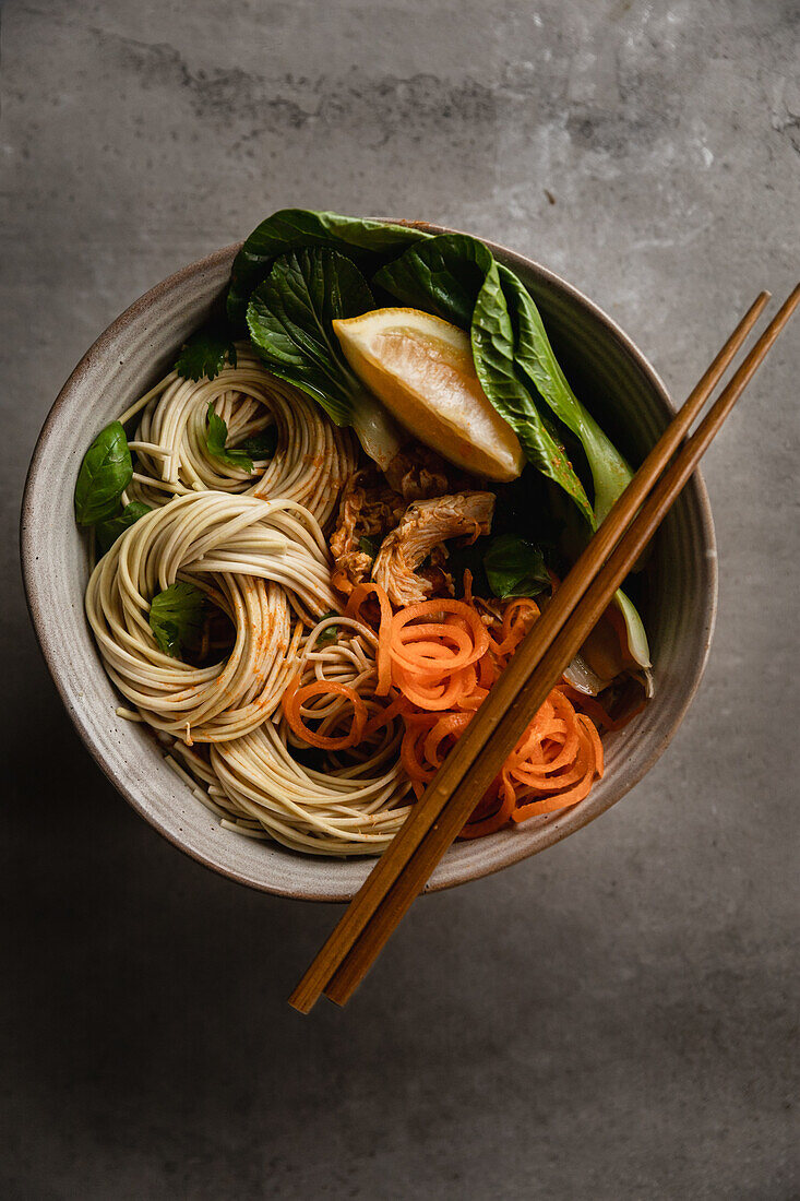 Asian noodle bowl with bok choy, spiralled carrots, fresh mint and lemon