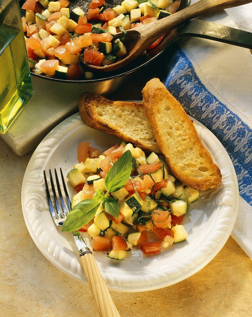 Tomaten-Zucchini-Ragout auf Teller mit Baguettescheiben