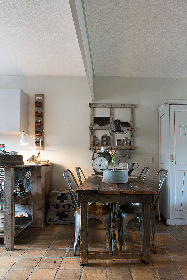 Old wooden table with metal chairs in front of kitchen island