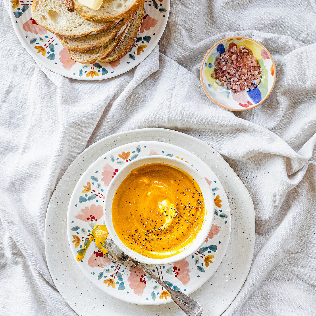 Orange pumpkin soup with a cream and pepper in white stoneware bowl