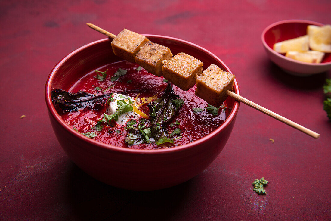 Vegan beetroot and carrot soup with fried tofu on a skewer