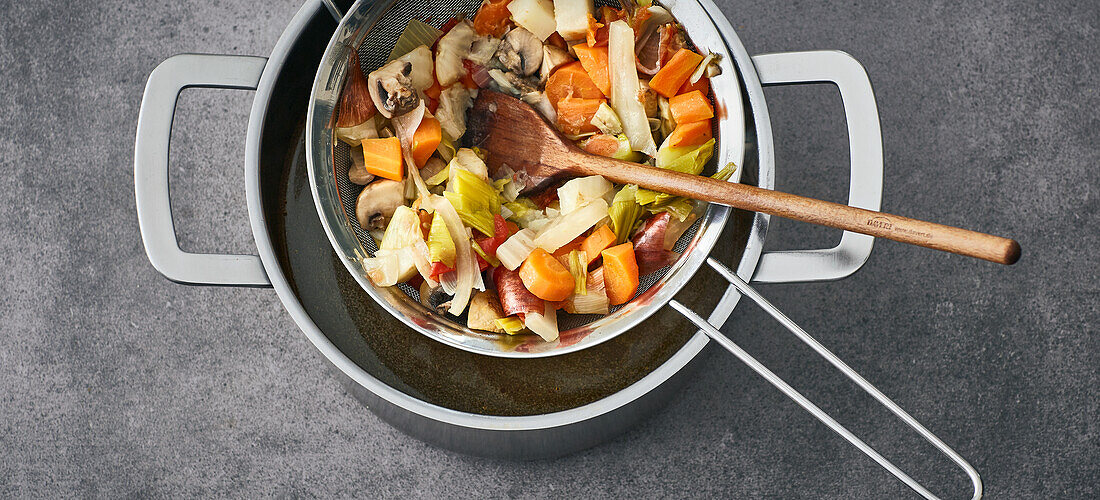 Make your own vegetable stock - straining the vegetables through a colander