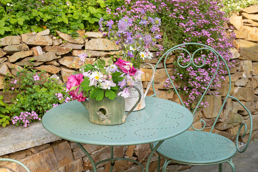 Kleine Blumensträuße auf Metalltisch im Garten