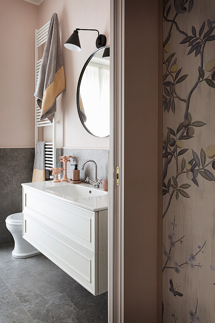 Blick auf weißen Waschtisch im Bad mit rosa Wänden und grauen Bodenfliesen