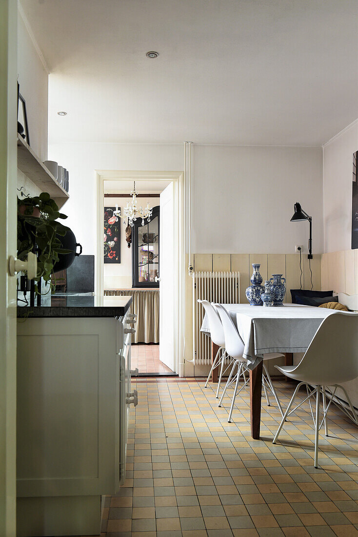 Long dining table with classic chairs in country kitchen with tiled floor