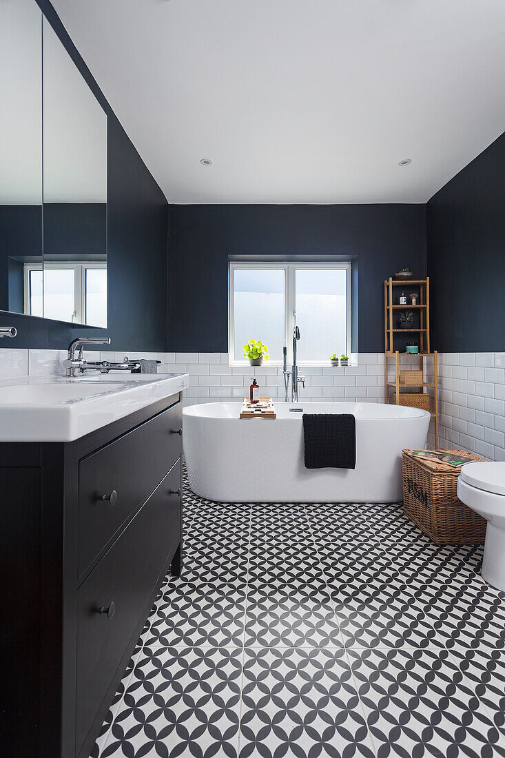 Washstand and freestanding bathtub in bathroom with patterned tiled floor