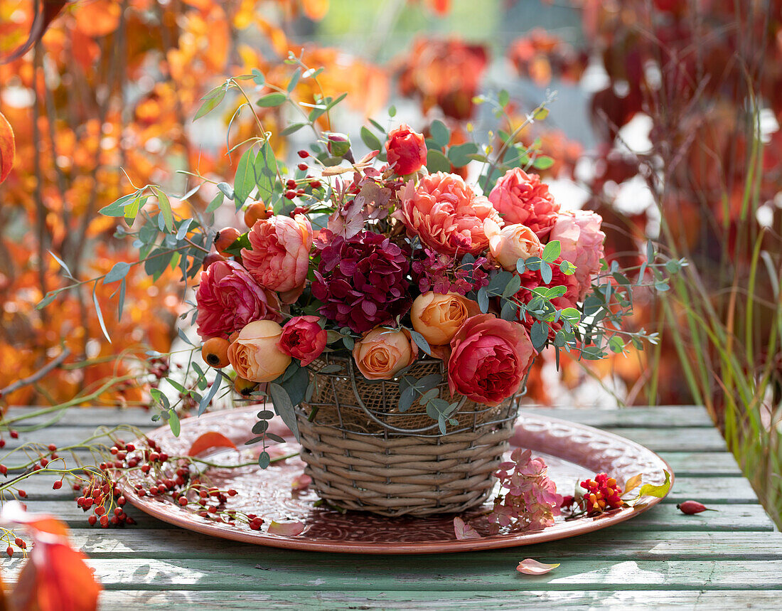 Lush autumn bouquet of roses, rose hips, hydrangea and eucalyptus in a basket