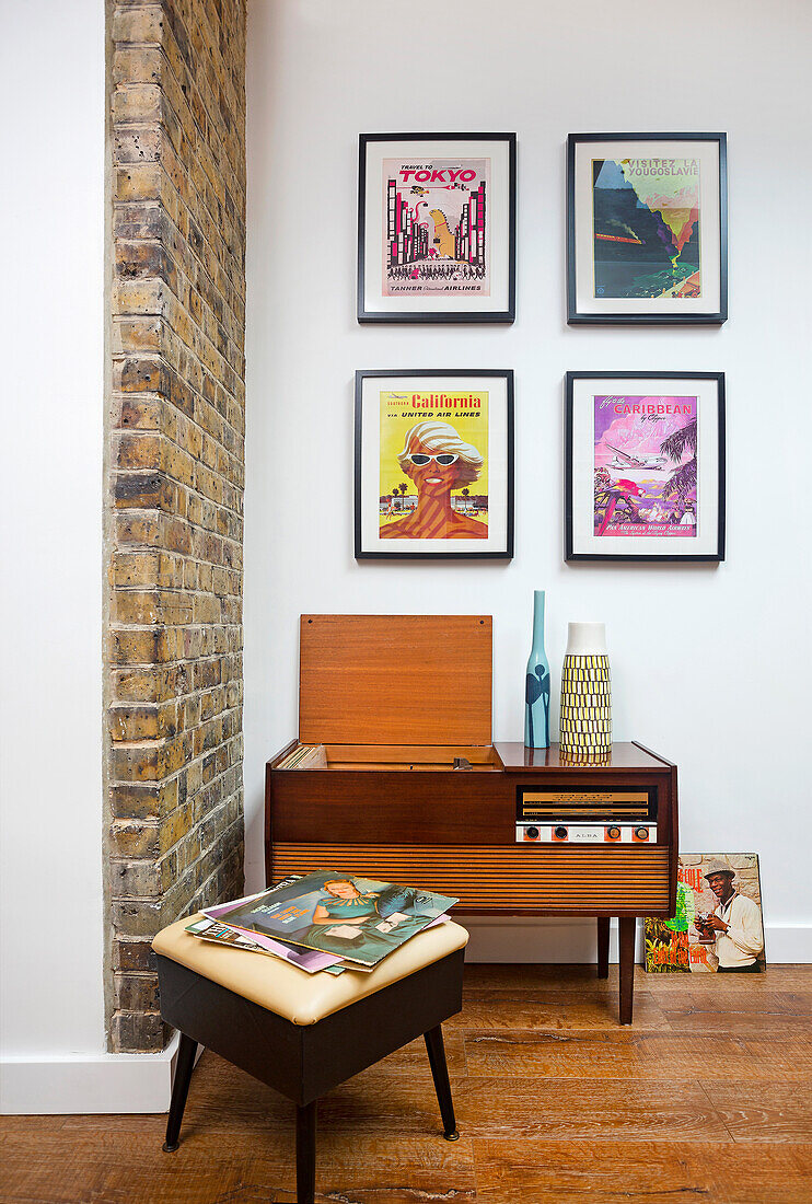 70s radio and stool below framed posters on wall