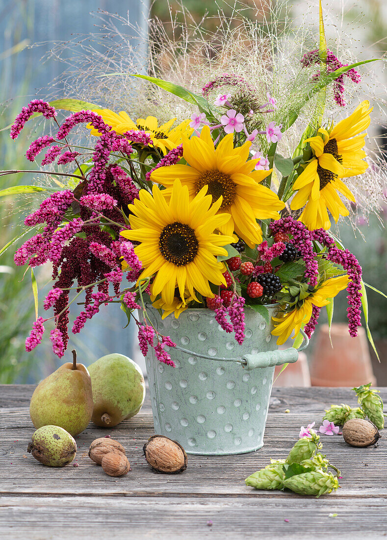 Autumn bouquet of sunflowers, knotweed, amaranth, phlox and witch grass, pears, walnuts and hops as decoration