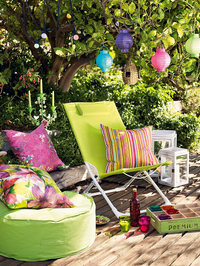 Deck chair, cushions, pillows, lanterns and paper lanterns on summer terrace
