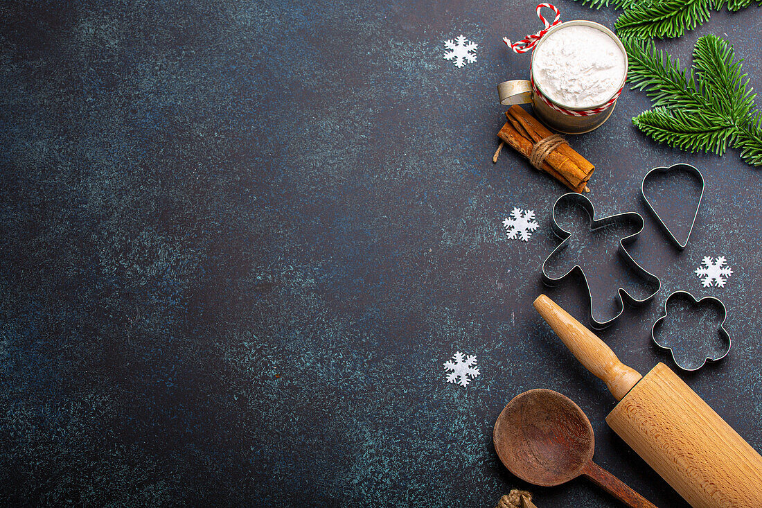 Christmas baking: kitchen tools, flour, fir tree branch, metal cookie cutters