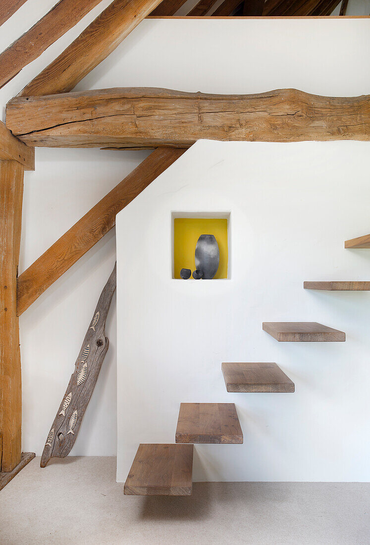 Floating staircase in a room with exposed wooden beams in a converted barn