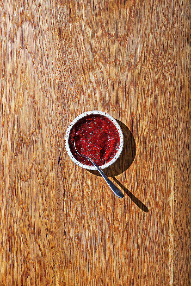 Cranberrysauce im Schälchen auf Holzuntergrund