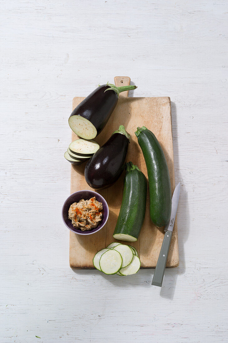 Aubergine cream, fresh aubergines and courgettes on a wooden chopping board