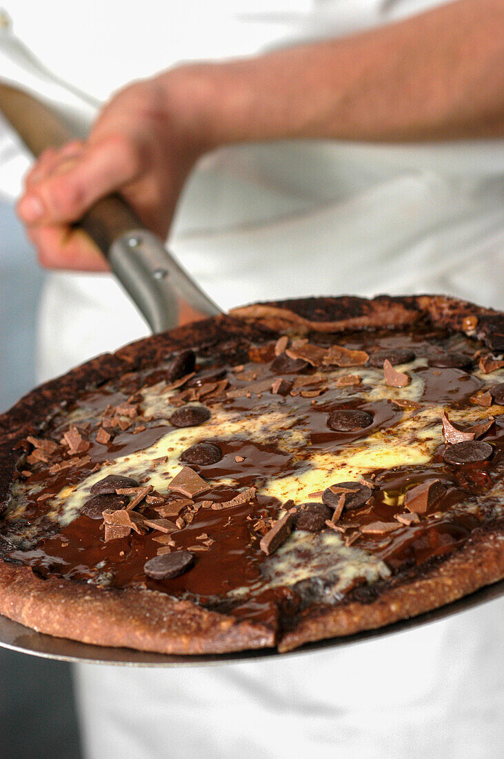 A chocolate pizza on a pizza paddle