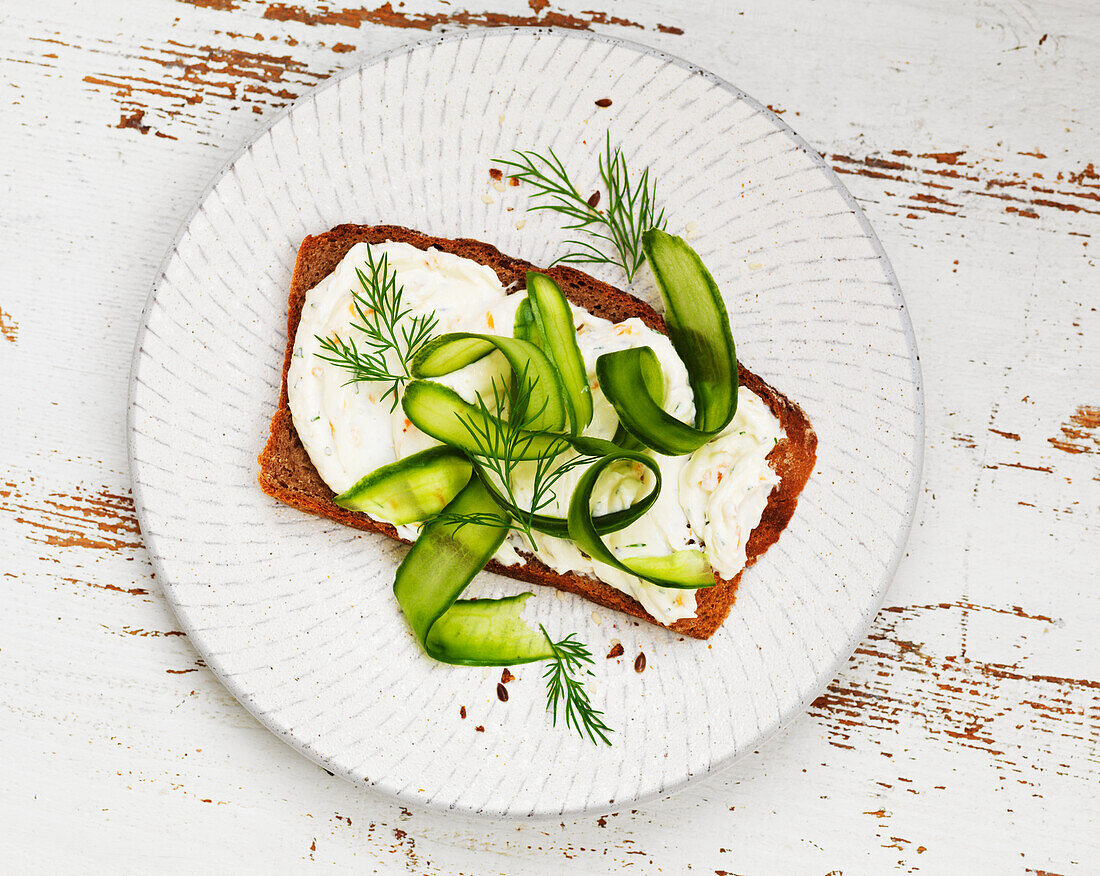 Bread topped with cream cheese, cucumber, and dill
