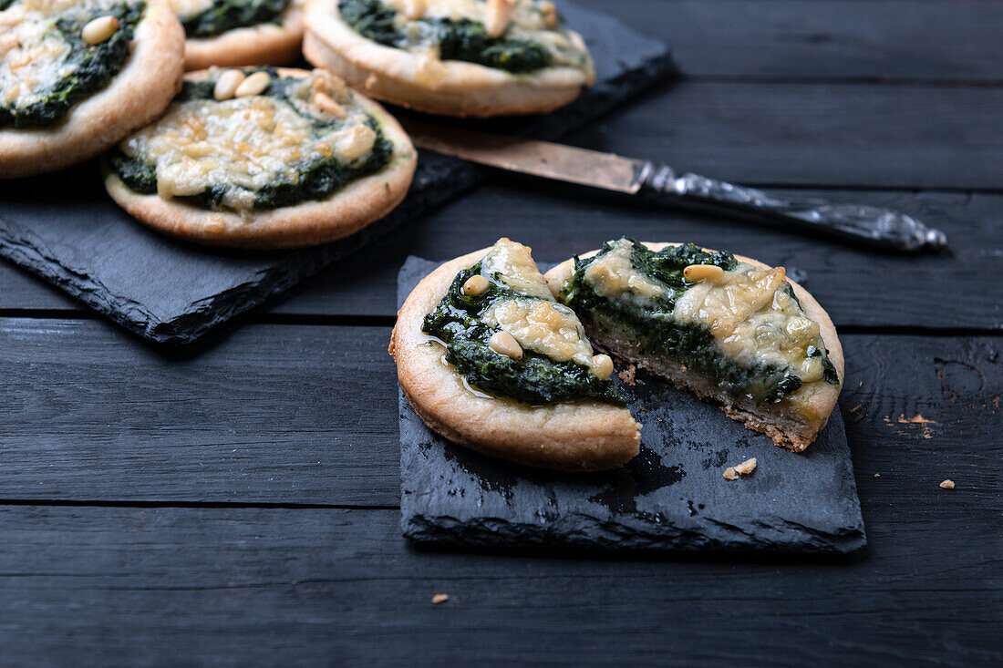 Vegan mini pizzas with spinach, pine nuts and almond cheese