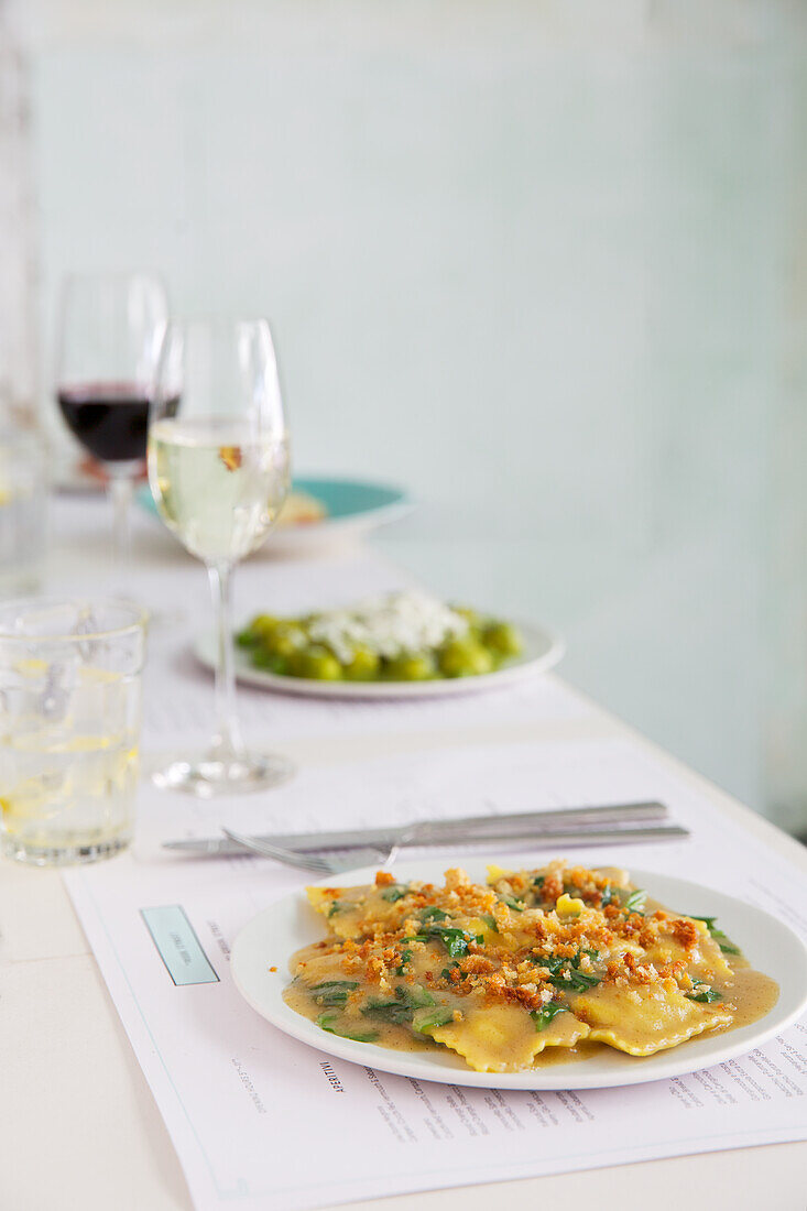 Ravioli mit Fleischfüllung und Gnocchi mit Pesto auf gedecktem Tisch