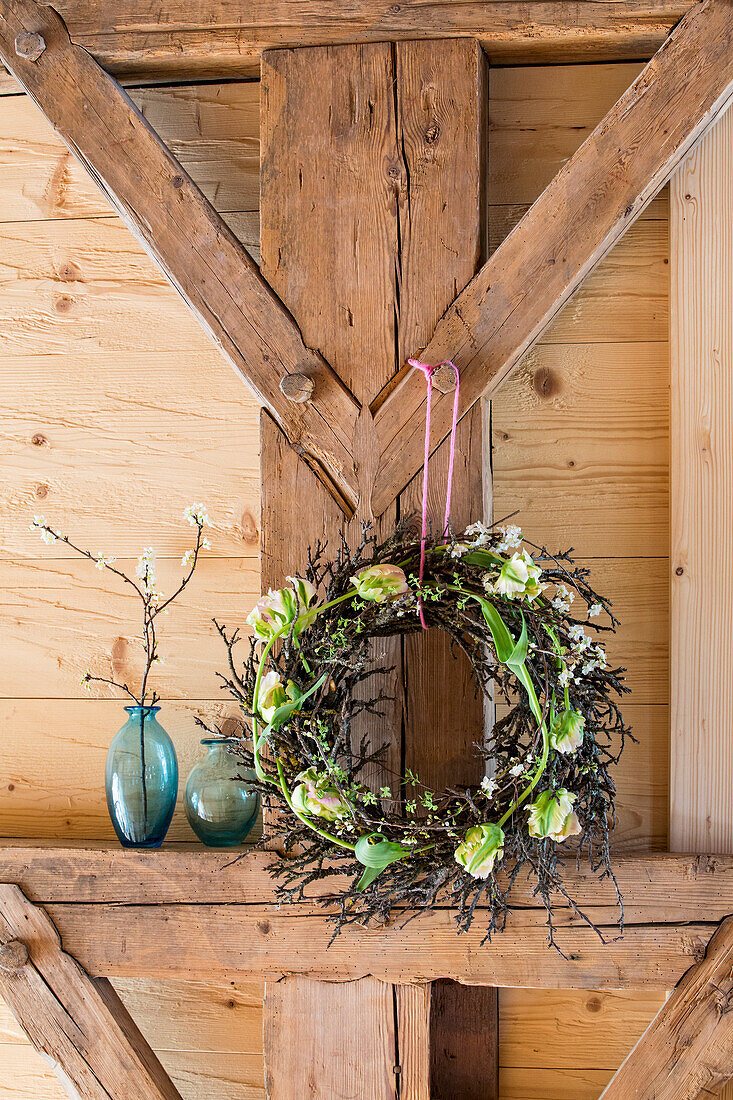 DIY-Kranz aus Tulpen und blühenden Zwetschgenzweigen am Holzbalken