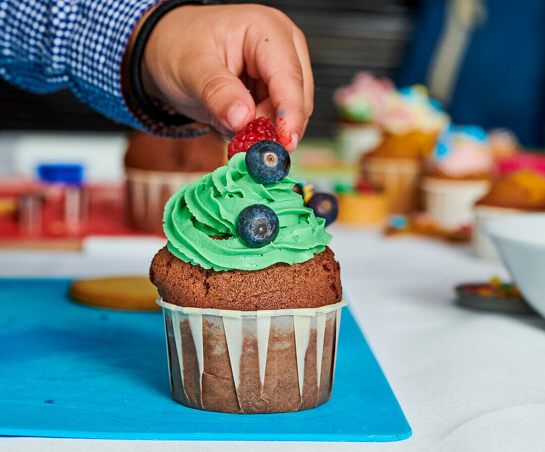 A cupcake with green frosting and berries