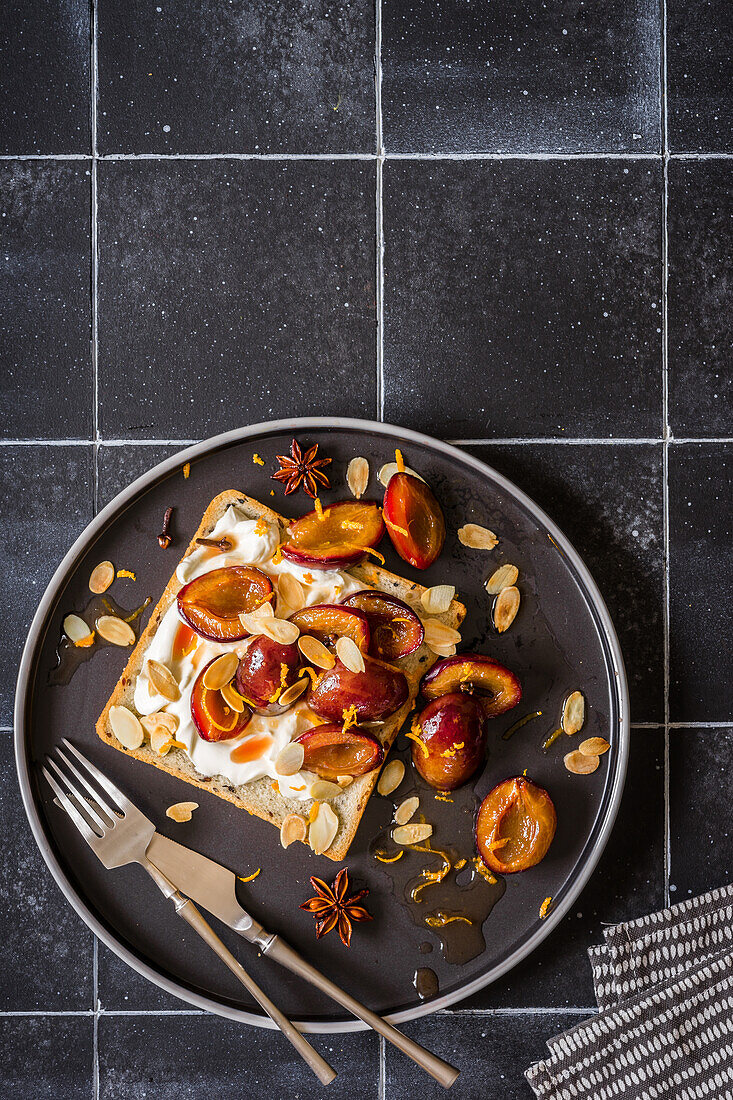 Toast with cream cheese and plums roasted with orange juice and almons flakes