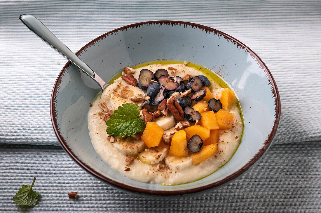 Millet porridge with persimmon, blueberries, banana, pecans and linseed oil