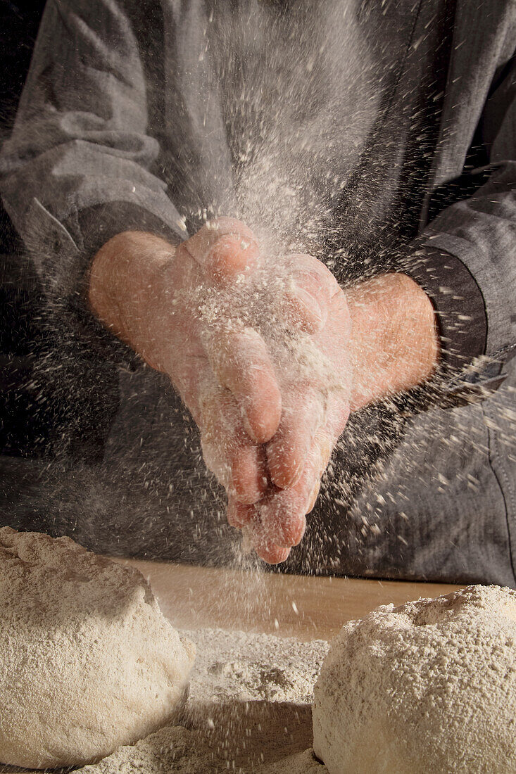 A woman knocking flour off her hands