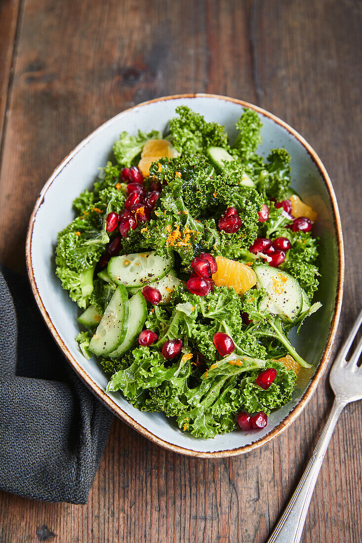 Kale salad with cucumber, pomegranate seeds and orange
