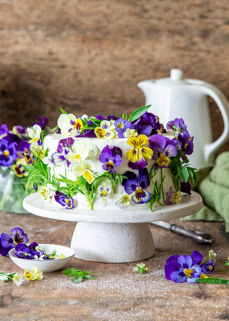 Vanilla buttercream cake with blueberries, decorated with violet blossoms