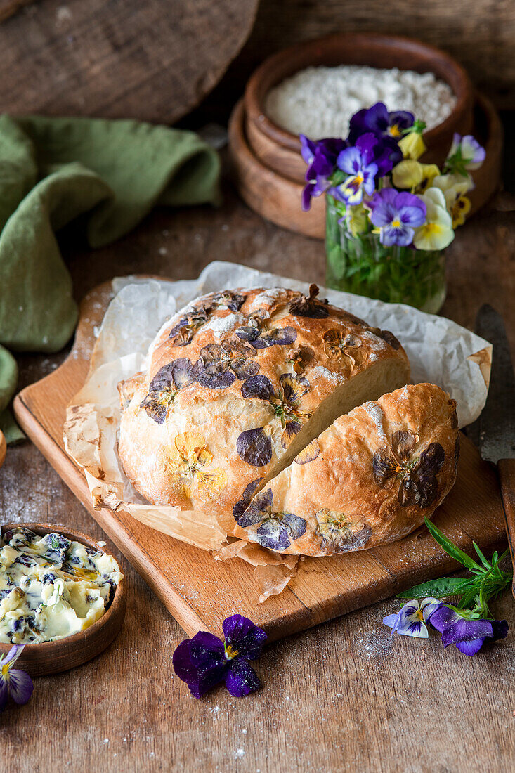 Bread with viola blossoms on a wooden cutting board