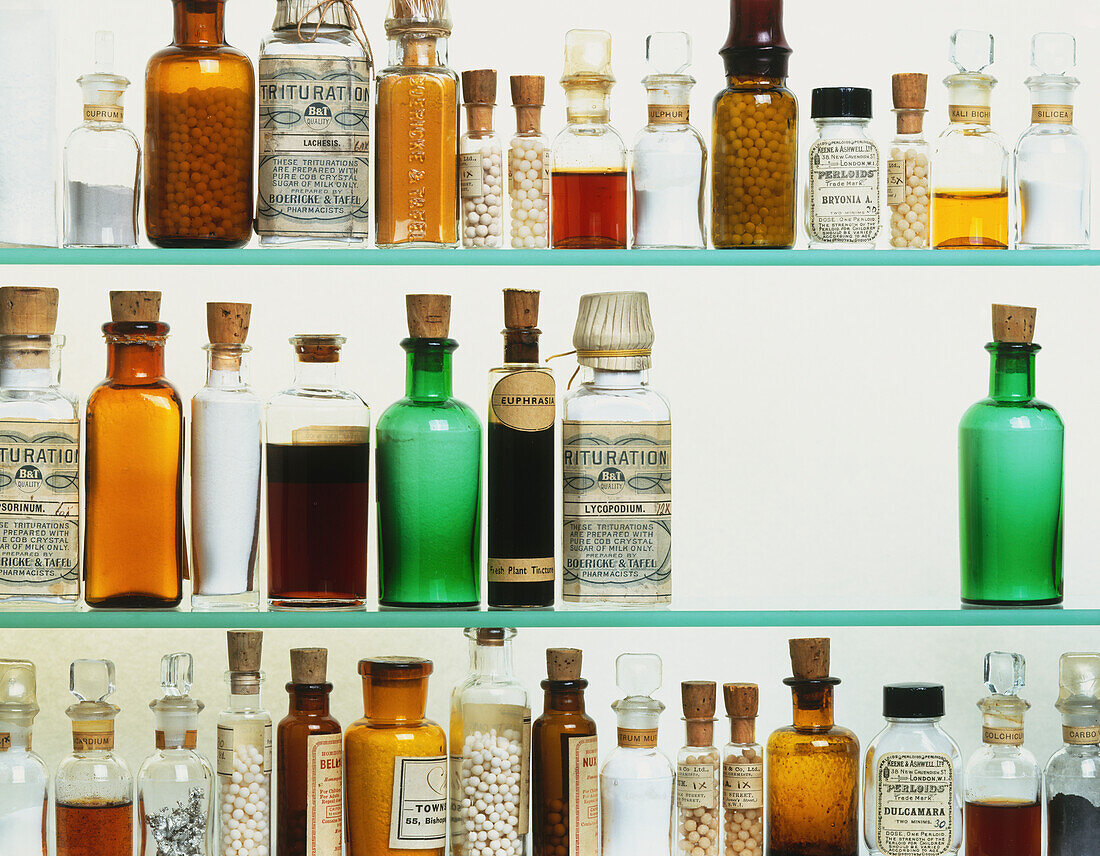 Bottles of homeopathic medicine on glass shelves