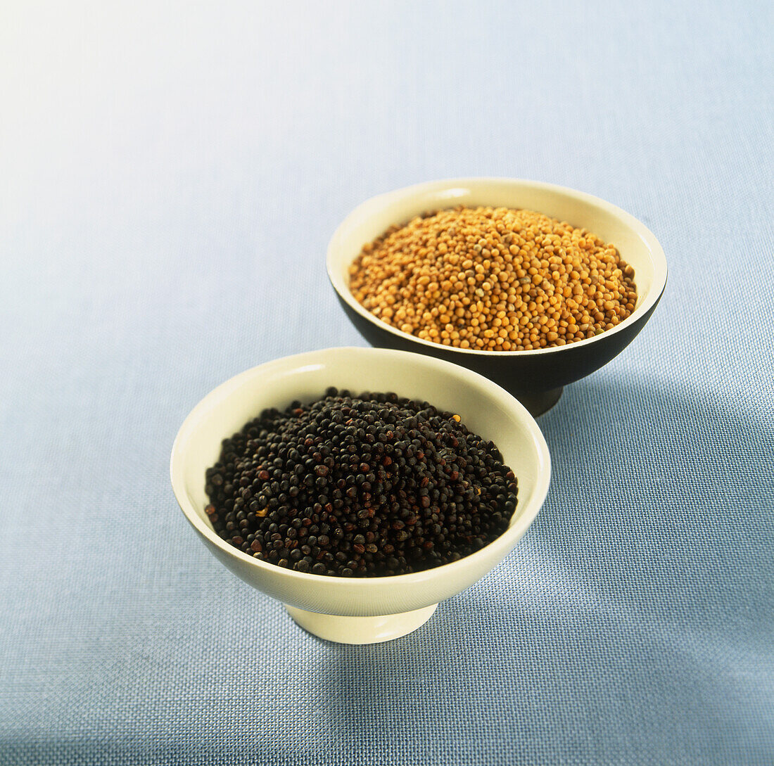 Black and white mustard seeds in ceramic bowls